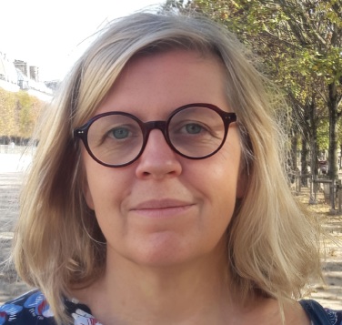 Portrait d’une femme souriante portant des lunettes dans un environnement extérieur naturel
